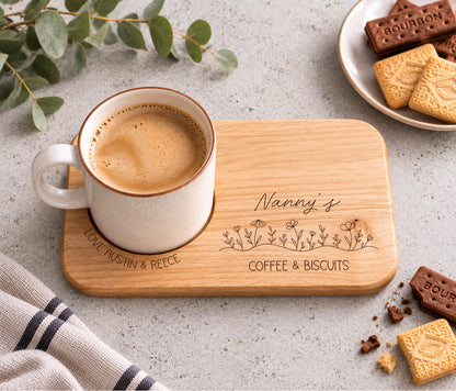 A rectangular wooden serving tray engraved with 'Nanny's coffee & BISCUITS' and a line of wildflowers, with love and the child / childrens name wrapped around the mug indent.