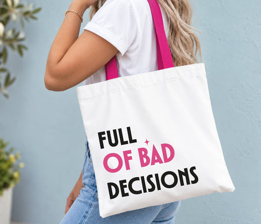 A woman wearing a white t-shirt and blue jeans carries a white canvas tote bag with bright pink straps. The bag features the text 'FULL OF BAD DECISIONS' in black and pink lettering.