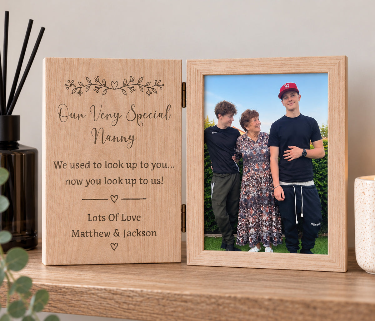 Book stlye solid oak photo frame with a photo of a nan and two boys one side and the other side  is a flat wood engraved with the wording 'we used to look up to you, now you look up to us' personalised with nanny at the top and the childrens names at the bottom.