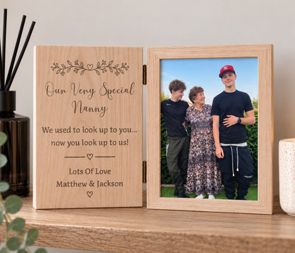 Book stlye solid oak photo frame with a photo of a nan and two boys one side and the other side  is a flat wood engraved with the wording 'we used to look up to you, now you look up to us' personalised with nanny at the top and the childrens names at the bottom.