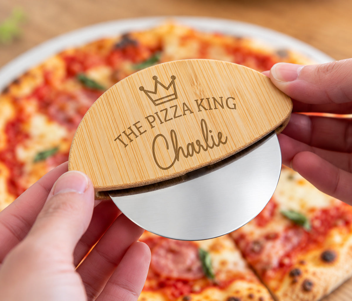 Wooden pizza wheel, engraved with a crown and the wording the pizza king, with a name underneath.